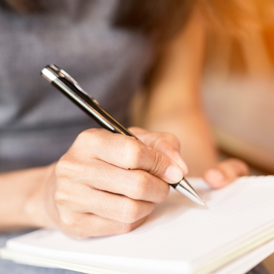 73_9282_15Mar2023150453_Close up of a hand holding a pen and notebook 540px.png